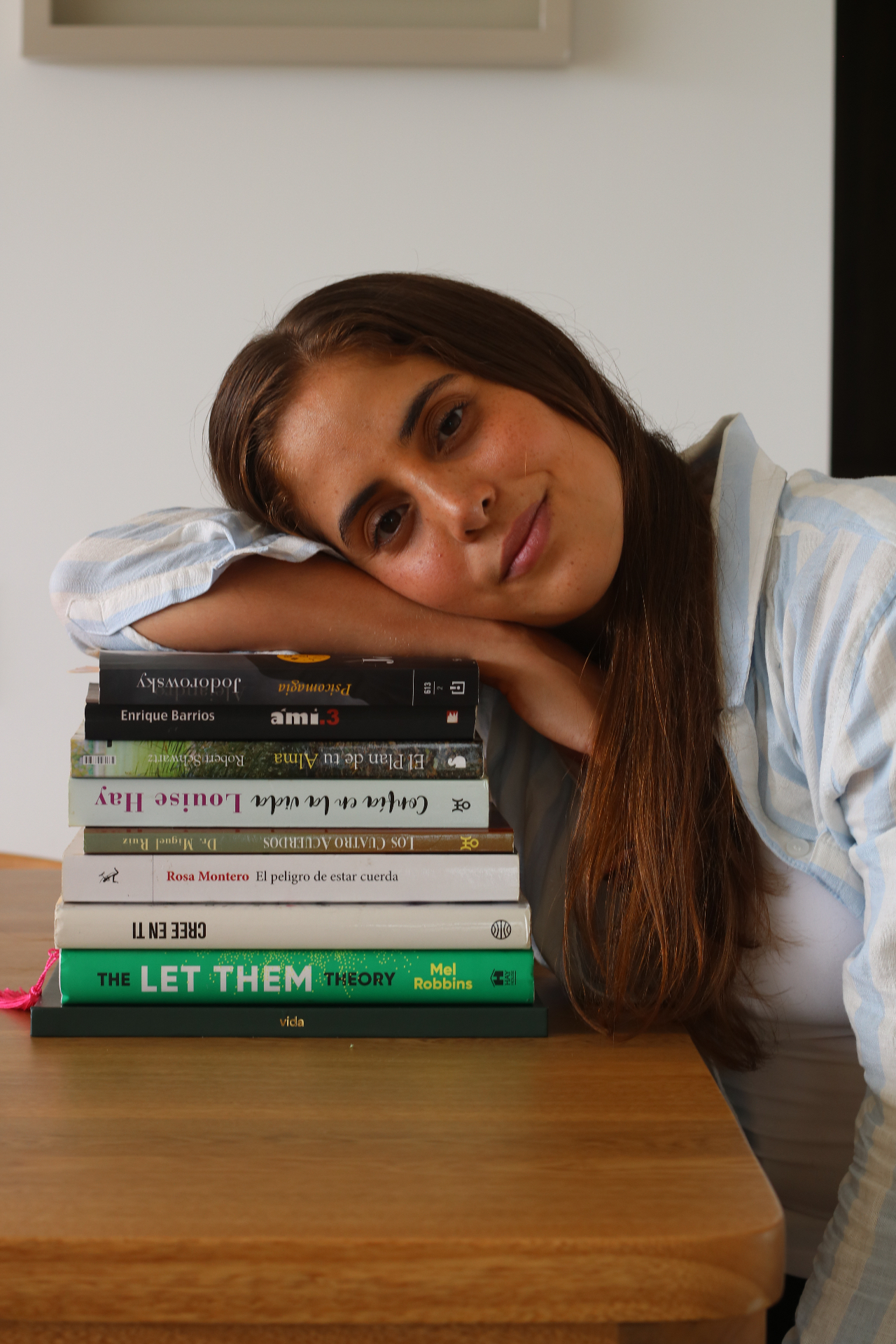 Isabella Rizo Romero apoyada en una pila de libros espirituales